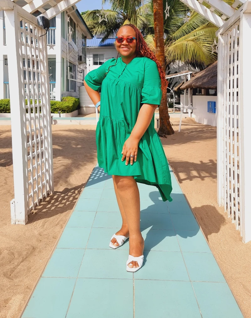 A woman in a green dress enjoying a serene beachside destination in Nigeria, ideal for a romantic honeymoon getaway