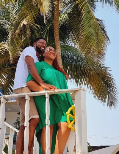 A couple enjoying a romantic moment at a tropical beachside destination in Nigeria, surrounded by palm trees.