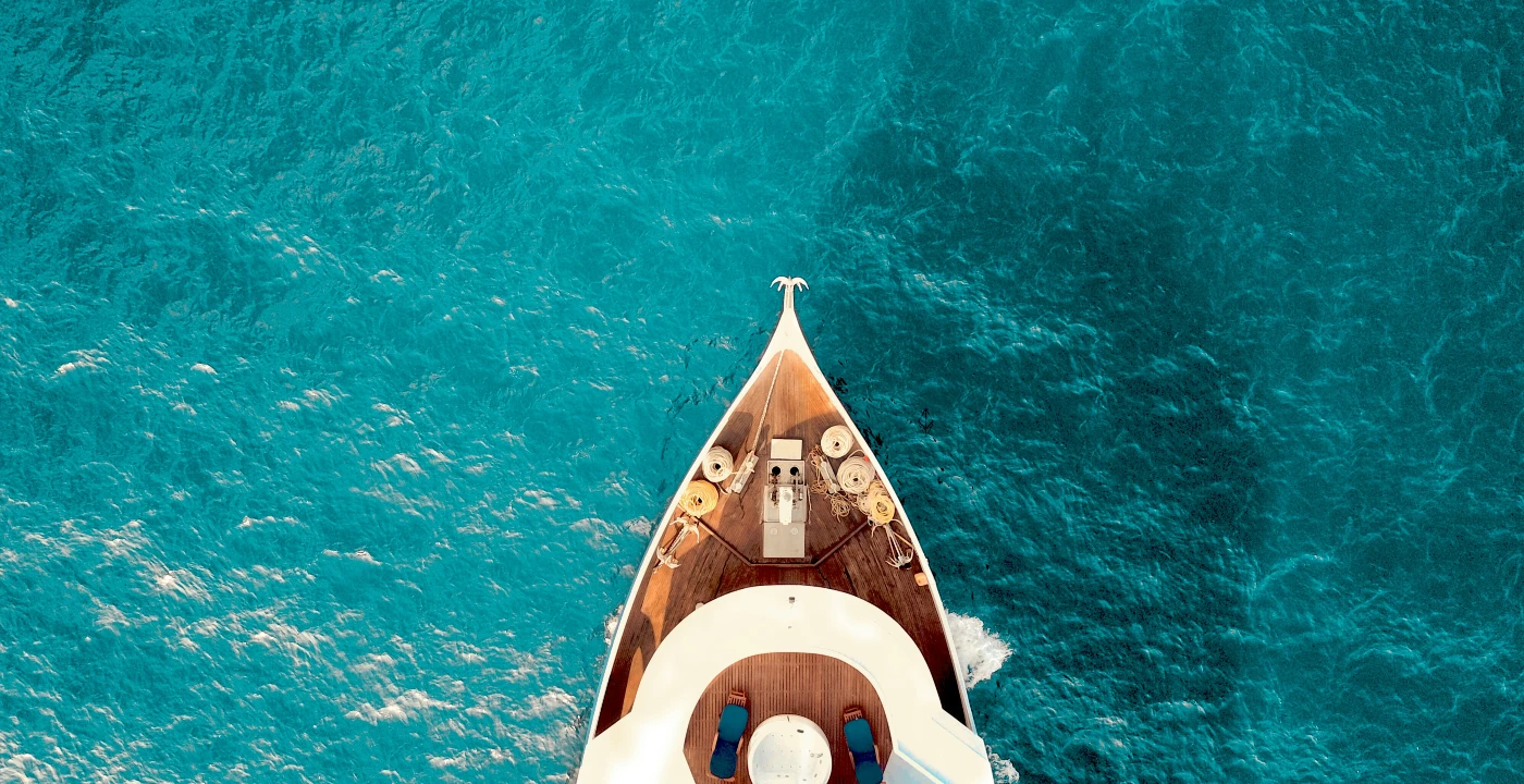 Top view of a luxury yacht cruising through clear turquoise waters, symbolizing an opulent honeymoon experience in 2025.