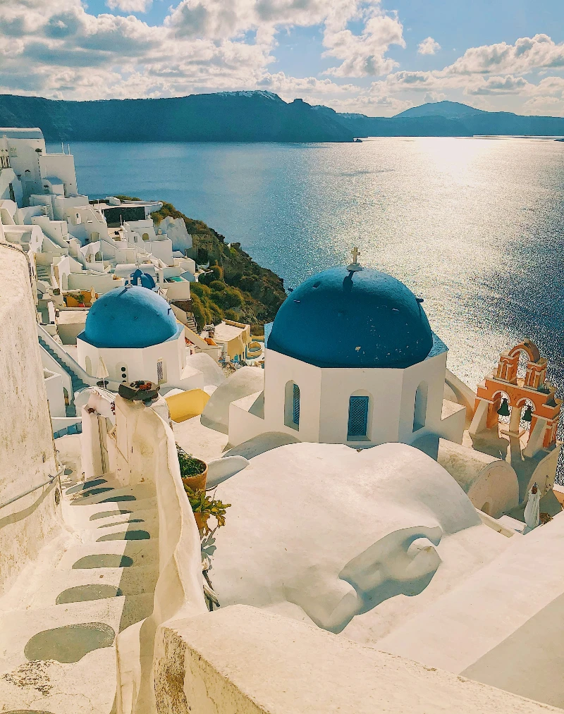 A view of the iconic blue-domed buildings and white architecture in Santorini, Greece, overlooking the Aegean Sea, a perfect honeymoon destination in 2025.