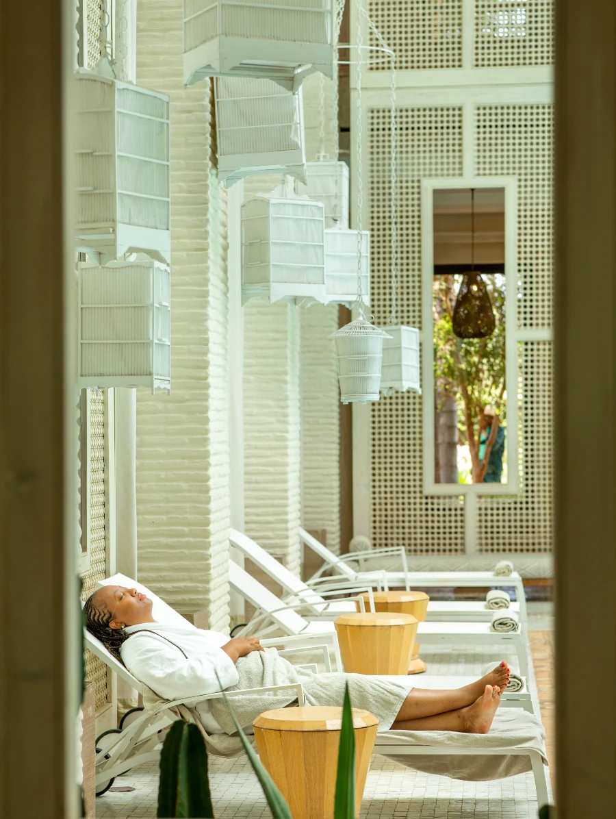 Woman relaxing in a luxury spa lounge surrounded by hanging white birdcages, enjoying a serene moment.