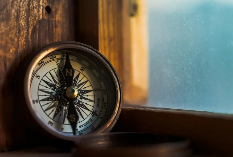 Vintage compass resting on a wooden windowsill, symbolizing travel and exploration - Lery Hago Travels