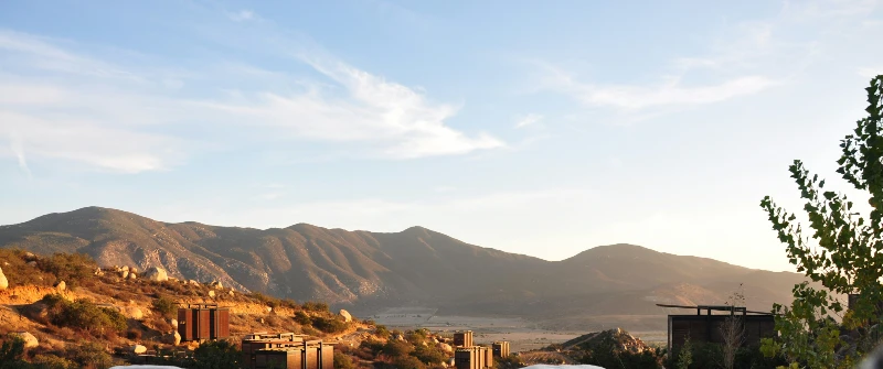 Scenic view of rolling hills and small cabins at sunset under a clear sky