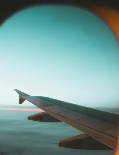 A view of an airplane wing through the window during a flight, highlighting tips on how to survive a long layover by Lery Hago Travels.