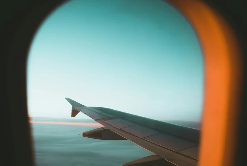 A view of an airplane wing through the window during a flight, highlighting tips on how to survive a long layover by Lery Hago Travels.