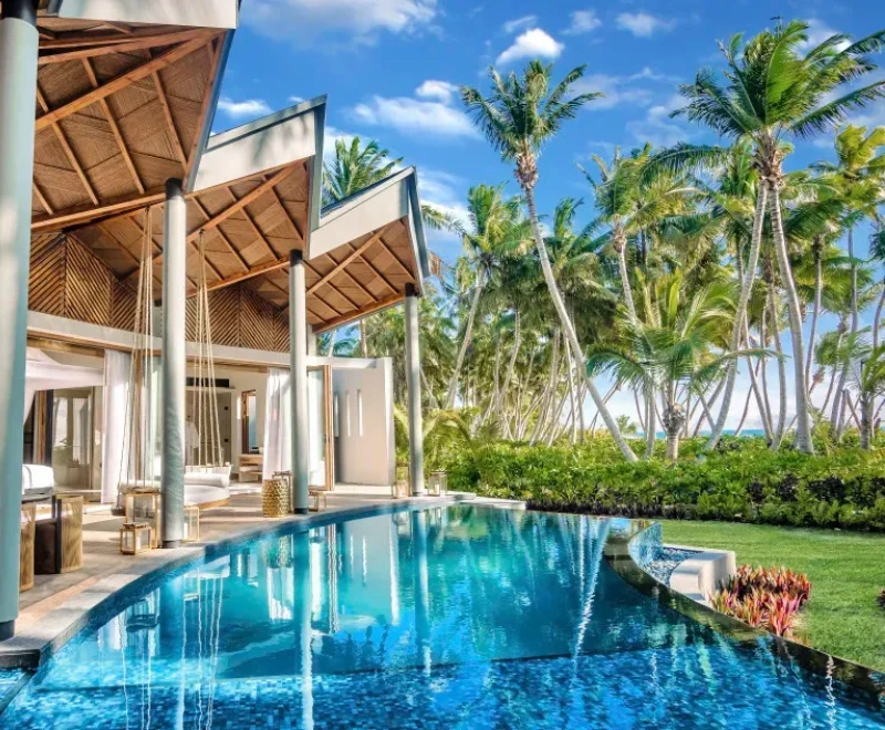 A luxurious villa with an infinity pool surrounded by lush palm trees in Seychelles, showcasing the ultimate paradise island experience.