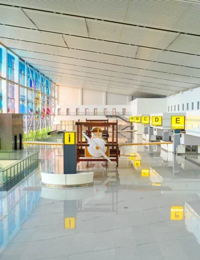 A spacious and modern Nigerian airport terminal with bright interior design, large windows, and directional signage for travelers.