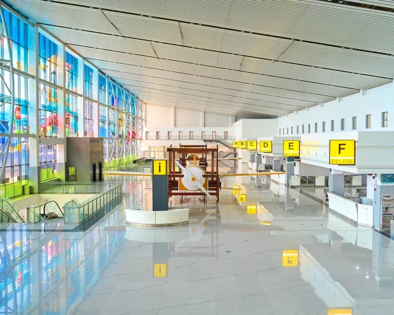 A spacious and modern Nigerian airport terminal with bright interior design, large windows, and directional signage for travelers.