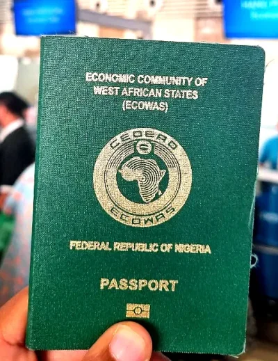 A close-up view of a Nigerian passport held at an airport check-in area, representing travel readiness and documentation.