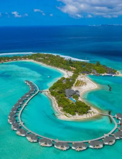 "A breathtaking aerial view of a luxury resort in the Maldives, featuring overwater villas surrounded by turquoise waters, showcasing why the Maldives sweeps major awards at the 2024 World Travel Awards."