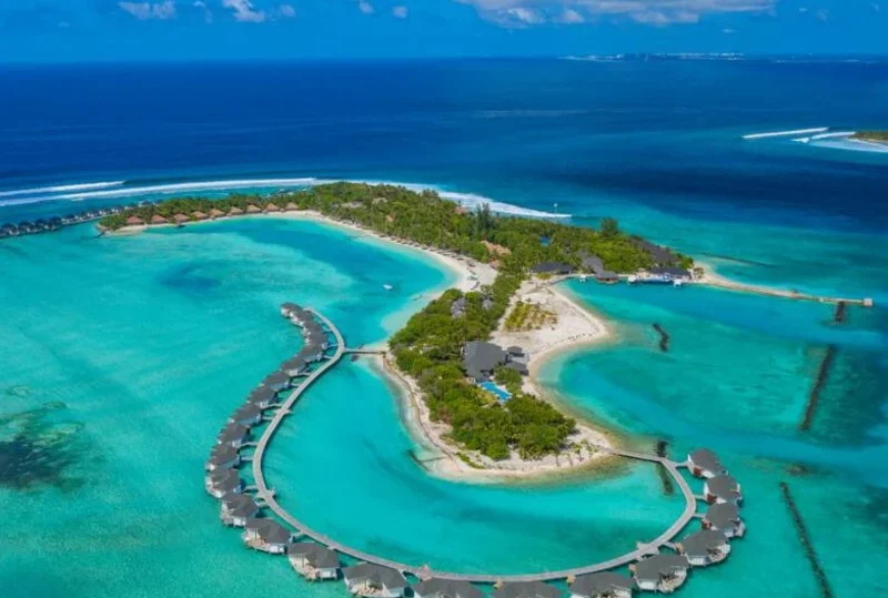 "A breathtaking aerial view of a luxury resort in the Maldives, featuring overwater villas surrounded by turquoise waters, showcasing why the Maldives sweeps major awards at the 2024 World Travel Awards."