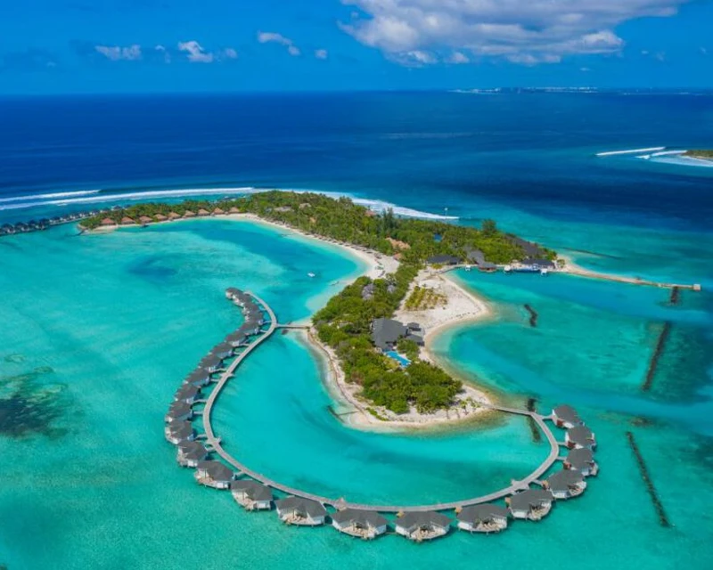 "A breathtaking aerial view of a luxury resort in the Maldives, featuring overwater villas surrounded by turquoise waters, showcasing why the Maldives sweeps major awards at the 2024 World Travel Awards."