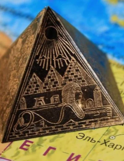 "A miniature pyramid souvenir featuring the Sphinx and pyramids, placed on a map of Egypt."