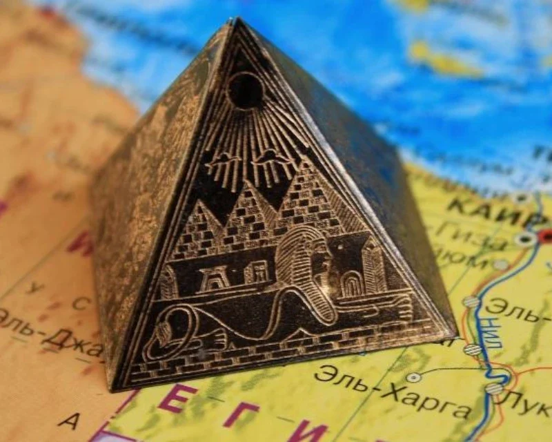 "A miniature pyramid souvenir featuring the Sphinx and pyramids, placed on a map of Egypt."