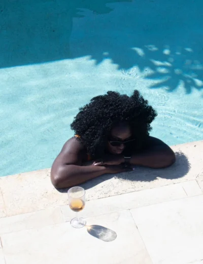 "A woman relaxing at the edge of a pool with a glass of wine nearby, showcasing a luxurious travel experience by Lery Hago Travels."