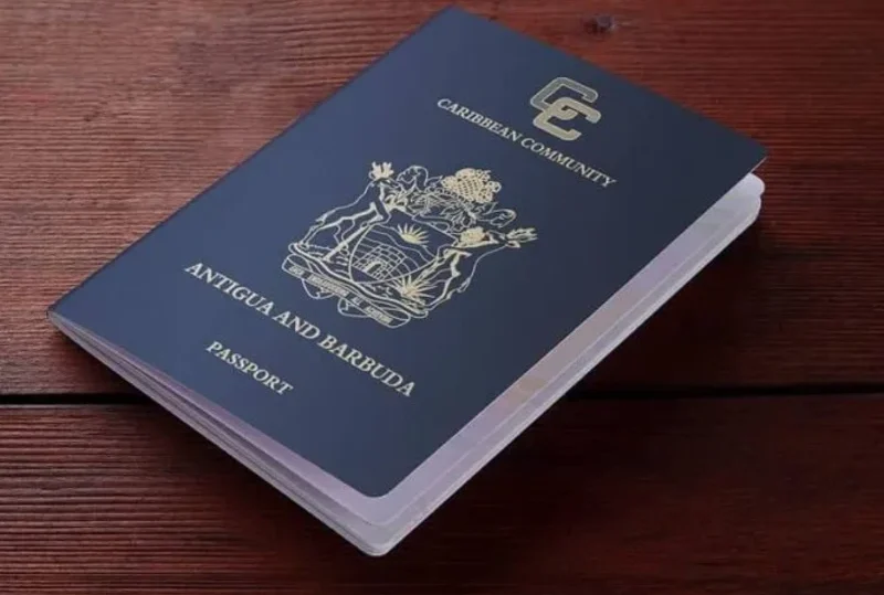 Antigua and Barbuda passport placed on a polished wooden surface, symbolizing global mobility through Caribbean citizenship