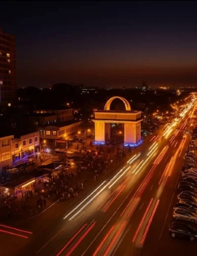 A vibrant night view of Accra featuring illuminated streets, Independence Arch, and festive lighting, symbolizing Ghana's night tourism initiative.