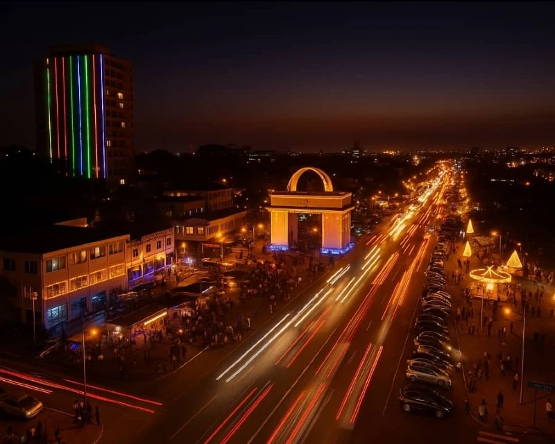 A vibrant night view of Accra featuring illuminated streets, Independence Arch, and festive lighting, symbolizing Ghana's night tourism initiative.