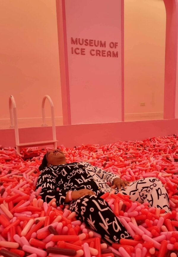 "A visitor revels in a whimsical Christmas in Singapore Package experience, lying in a sea of pink candy replicas at the Museum of Ice Cream."