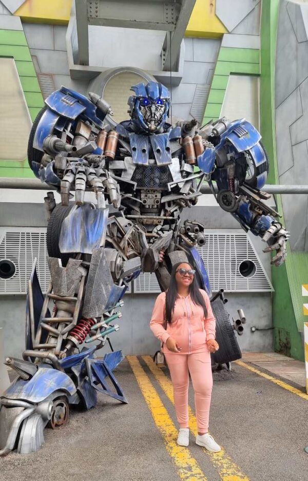 "A visitor posing confidently in front of a grand robotic sculpture in Singapore, showcasing the city's cutting-edge attractions included in the luxury getaway package."