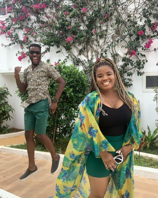 "Two happy individuals in vibrant clothing, celebrating a Zanzibar Festive Season Getaway, with a backdrop of lush bougainvillea."