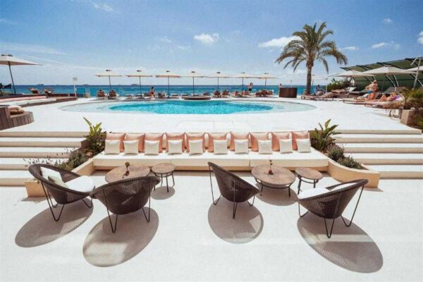 "Luxurious poolside lounge with stylish chairs and umbrellas overlooking the sea, part of the Paris Love Getaway experience from www.leryhago.com."