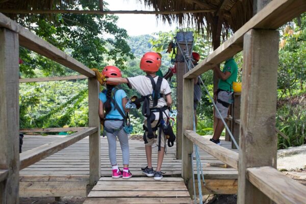 "Children in safety gear preparing for a zipline adventure in Nairobi's lush surroundings"