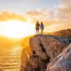 "A couple stands hand-in-hand on the cliff edge in Malta, overlooking the sea at sunset, epitomizing a romantic Malta Historical Getaway, image courtesy of www.leryhago.com."
