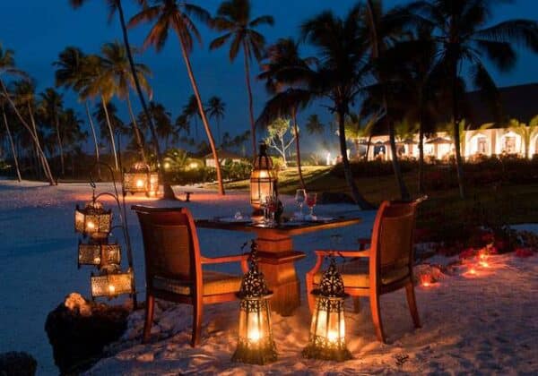 "Intimate beachfront dinner setup at night with lanterns on a Zanzibar Summer Holiday, inviting romance at www.leryhago.com."