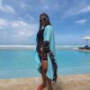 "Elegant woman in stylish beachwear posing by an infinity pool overlooking the Zanzibar sea, perfect for a summer holiday at www.leryhago.com."