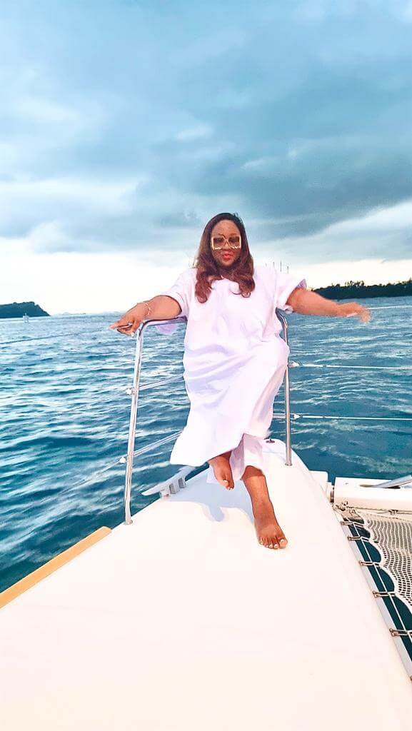 "A woman exudes elegance on a luxurious yacht in Singapore, her serene pose complementing the tranquil seascape at dusk."
