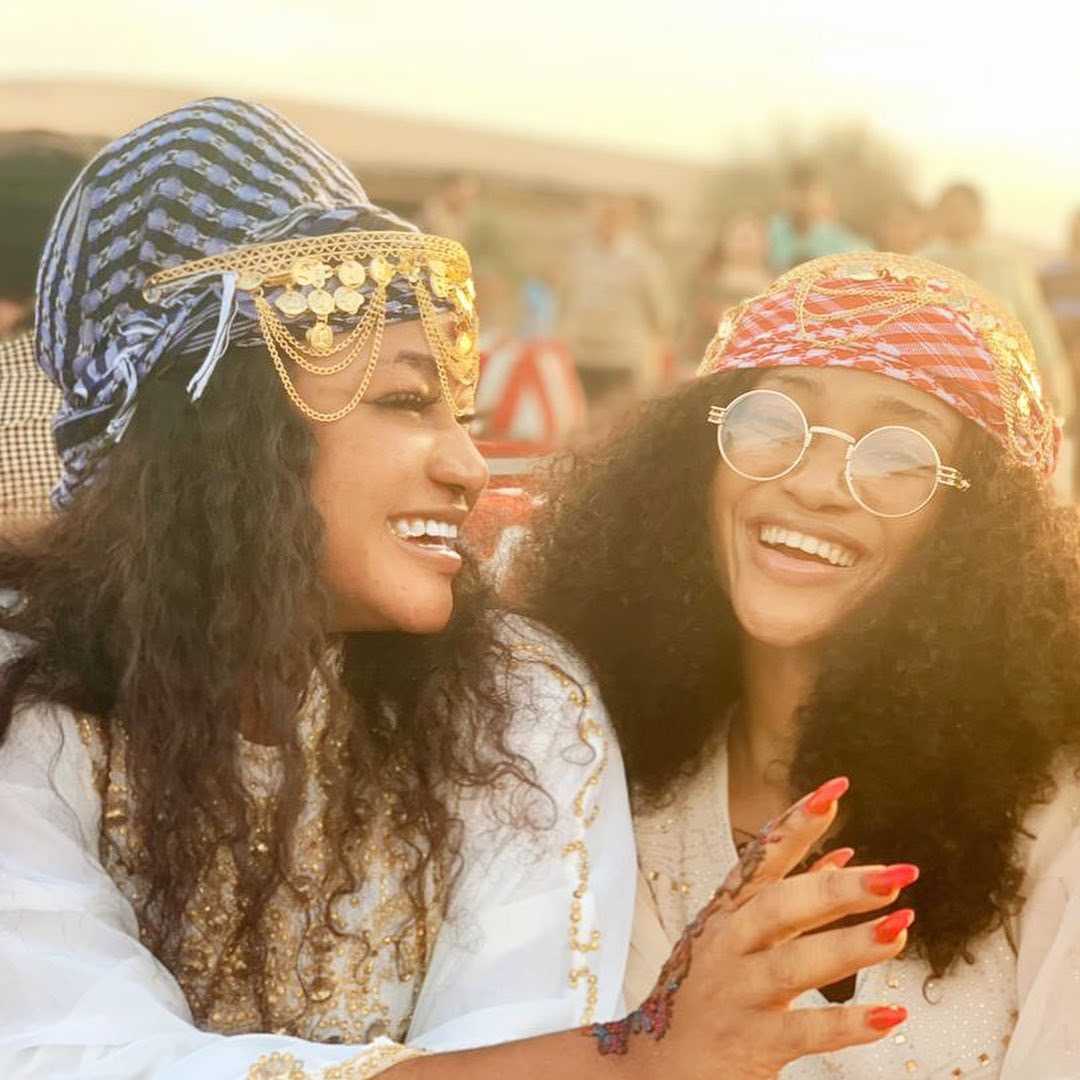 "Two friends sharing a joyous moment in traditional headwear, their laughter symbolizing the joy of cultural immersion on a leisure vacation - www.leryhago.com."
