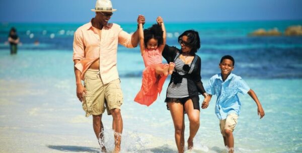"Family joyfully walking along the shallow waters of Mombasa beach during Christmas"
