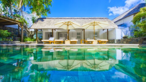 "Inviting poolside view at 20 Degrees Sud resort in Mauritius, with crystal clear waters, white umbrellas, and loungers set against a backdrop of tropical luxury."