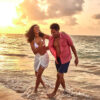 "Laughing couple enjoying a beach walk at sunset, embodying the joy of the Luxurious Christmas St. Lucia Package, available at www.leryhago.com"