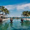 "Elegant resort infinity pool lined with palm trees leading to the ocean in Vietnam, part of our Romantic Getaway Package."