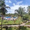 "An idyllic view of a poolside retreat with lush palm trees and manicured gardens, under the sunny skies of Nairobi Mauritius, inviting a Pre-Christmas Escape."