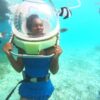 "Woman experiencing underwater walking with a helmet, surrounded by tropical fish, enjoying the aquatic Pre-Christmas Magic in Mauritius."