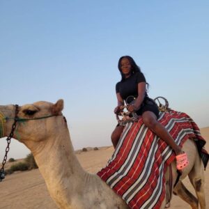 "Woman enjoying a serene camel ride at sunset in the Dubai desert, a unique feature of the Christmas Dubai Luxury Package."