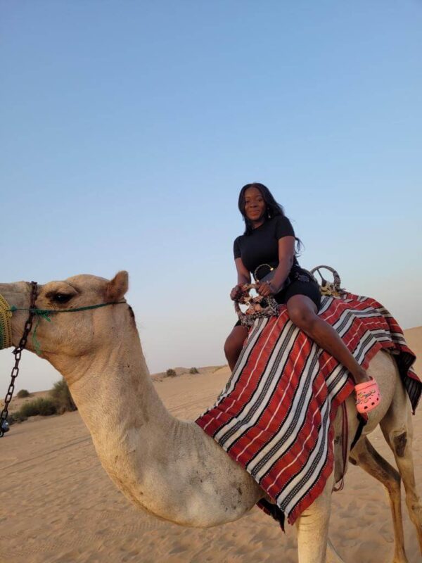 "Woman enjoying a serene camel ride at sunset in the Dubai desert, a unique feature of the Christmas Dubai Luxury Package."