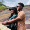 "A couple shares a tender moment overlooking the multi-colored earthy hues of Nairobi Mauritius's landscape, symbolizing a Pre-Christmas Escape filled with romance."
