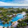 "Aerial view of a luxurious resort in Vietnam featuring a sprawling pool, palm trees, and oceanfront, perfect for a romantic getaway package."