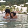 "A couple sharing a tender moment in the sea with a backdrop of St. Lucia's scenic resort, part of the Luxurious Christmas St. Lucia Package at www.leryhago.com"