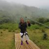 "Man poised for zip-lining adventure amidst misty hills, part of the Christmas Kigali Nairobi Package"