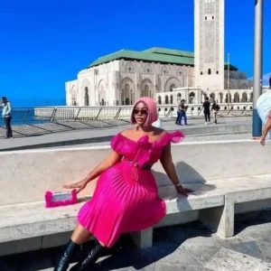 "Fashion-forward traveler in a vibrant pink dress posing in front of an iconic mosque in Doha, a sightseeing highlight from the Qatar Doha Package | www.leryhago.com"
