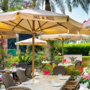 "Outdoor dining oasis surrounded by blooming flowers at a restaurant included in the Qatar Doha package - visit www.leryhago.com to book"