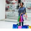 "Joyful woman enjoying a shopping spree in Doha's premier mall, carrying colorful bags, featured in www.leryhago.com's Qatar Doha Package."