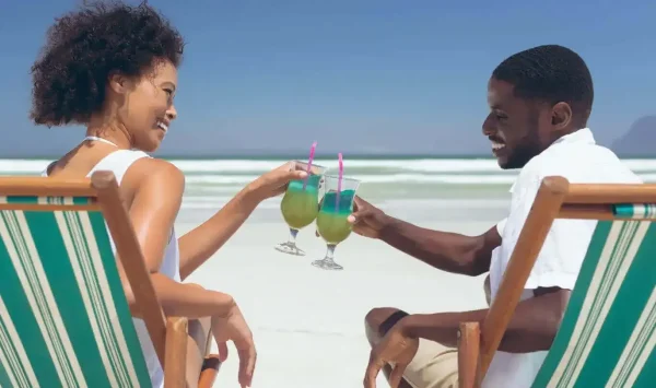 A smiling couple toasting with drinks on a Cape Verde beach