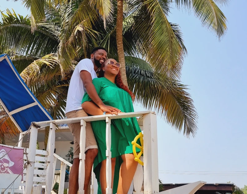 A couple enjoying a romantic moment at a tropical beachside destination in Nigeria, surrounded by palm trees.