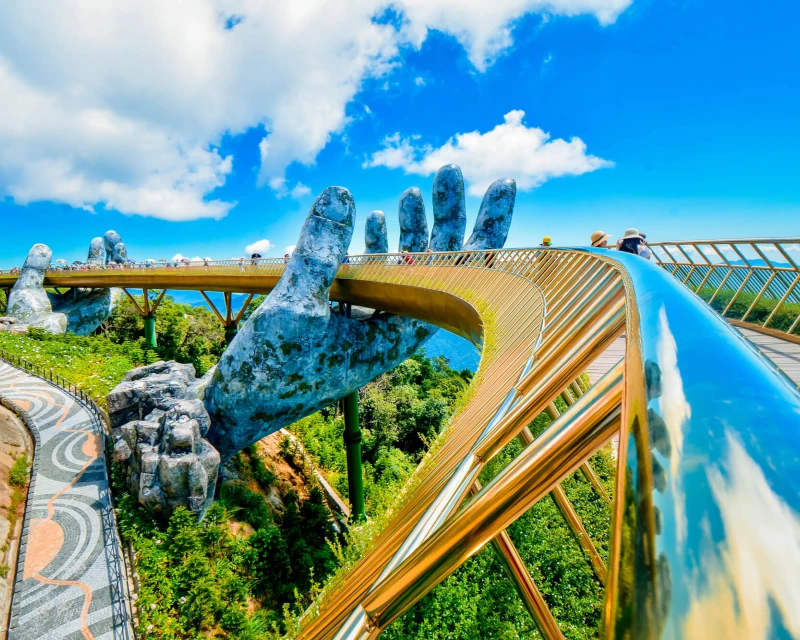 Stunning view of the Golden Bridge at Ba Na Hills, Vietnam, featuring giant stone hands holding the bridge under a clear blue sky.